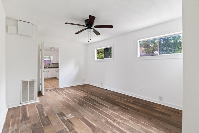 empty room featuring visible vents, a ceiling fan, baseboards, and wood finished floors