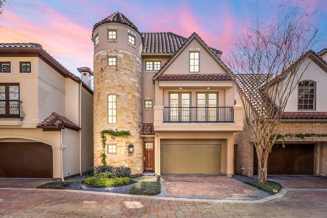 view of front of home with a tile roof, stucco siding, a balcony, a garage, and driveway