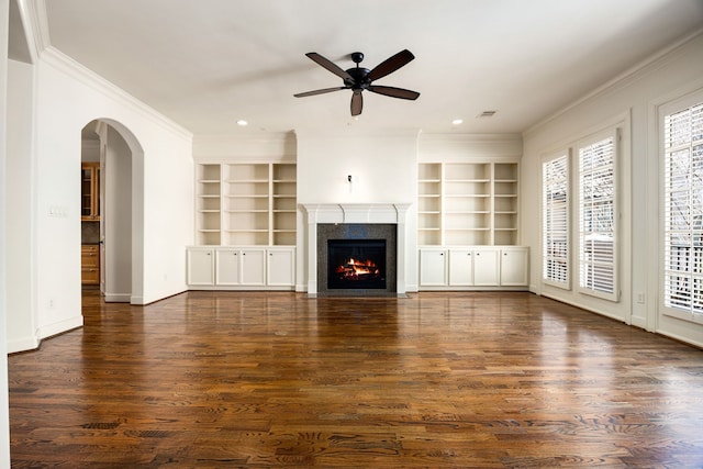 unfurnished living room with visible vents, a fireplace with flush hearth, arched walkways, dark wood-style flooring, and ornamental molding