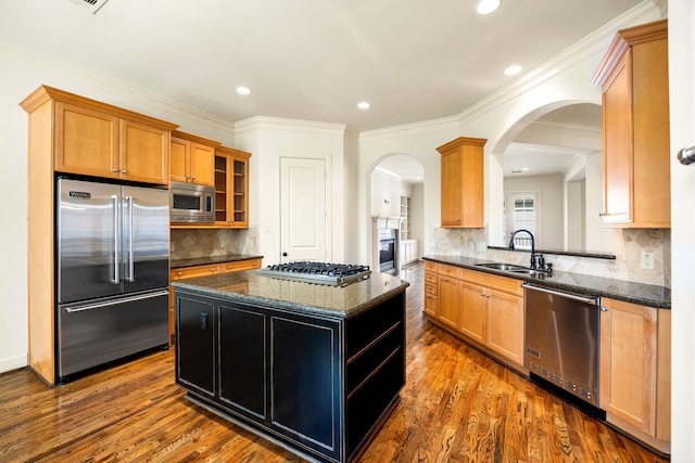 kitchen featuring a sink, dark wood-type flooring, built in appliances, and a kitchen island