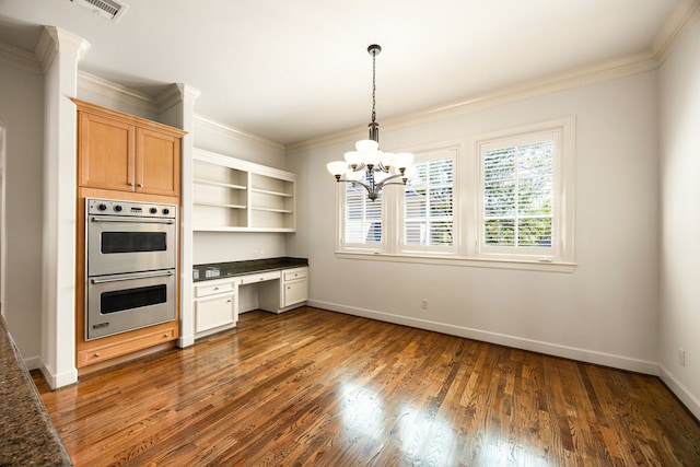 kitchen featuring built in study area, stainless steel double oven, dark wood-style flooring, ornamental molding, and dark countertops