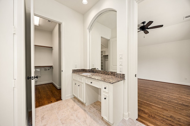 bathroom with baseboards, vanity, a ceiling fan, and wood finished floors