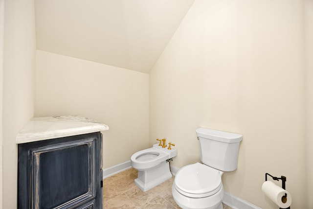 bathroom with tile patterned flooring, baseboards, toilet, a bidet, and lofted ceiling