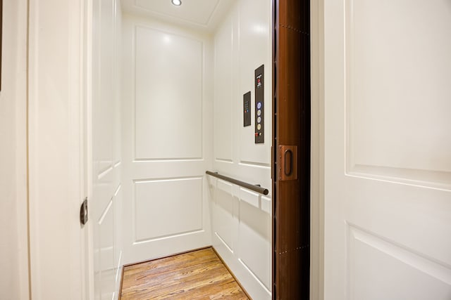 interior space with light wood-style flooring, elevator, and recessed lighting