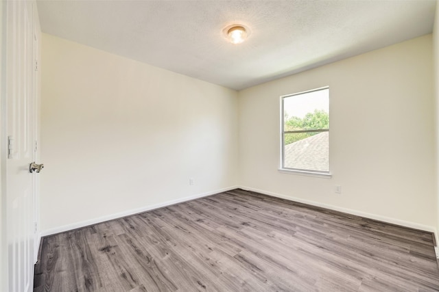 empty room with baseboards, a textured ceiling, and wood finished floors