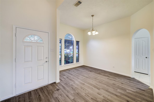 entryway with visible vents, baseboards, a chandelier, wood finished floors, and arched walkways