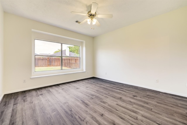 unfurnished room featuring visible vents, baseboards, a ceiling fan, and dark wood-style flooring