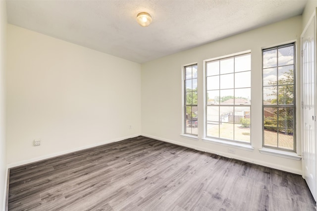 spare room with wood finished floors, baseboards, and a textured ceiling