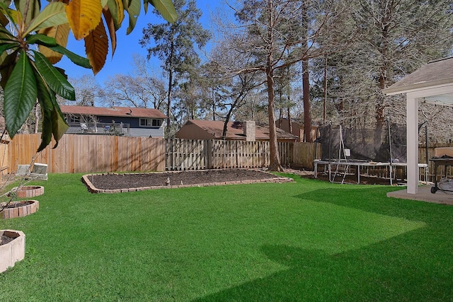 view of yard with a trampoline and a fenced backyard