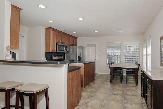 kitchen with recessed lighting, stainless steel appliances, a kitchen bar, and visible vents