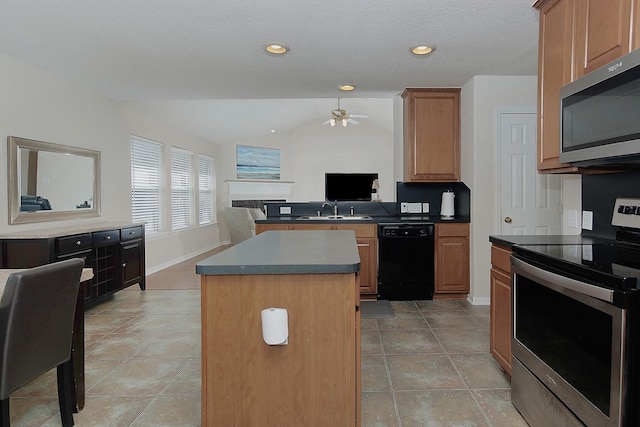 kitchen featuring a ceiling fan, a sink, a kitchen island, appliances with stainless steel finishes, and a peninsula