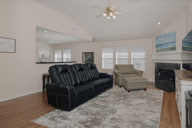 living area with visible vents, baseboards, vaulted ceiling, a fireplace, and wood finished floors