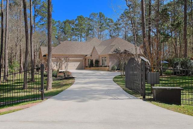 french country style house with brick siding, a front lawn, a fenced front yard, concrete driveway, and an attached garage