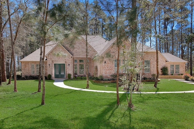 view of front of home with brick siding, french doors, and a front lawn