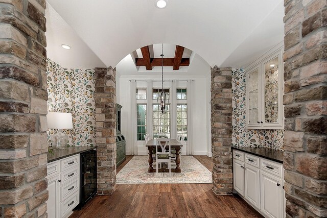 unfurnished dining area with beverage cooler, dark wood-style floors, arched walkways, and vaulted ceiling