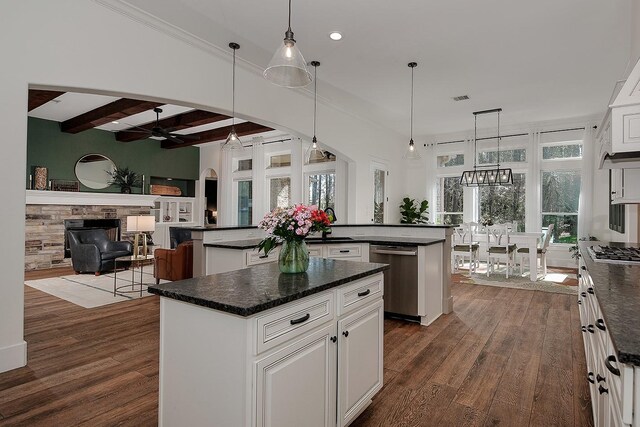 kitchen featuring dark wood-style floors, stainless steel appliances, dark countertops, beamed ceiling, and a center island