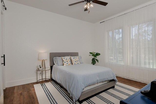 bedroom with multiple windows, wood finished floors, baseboards, and ceiling fan