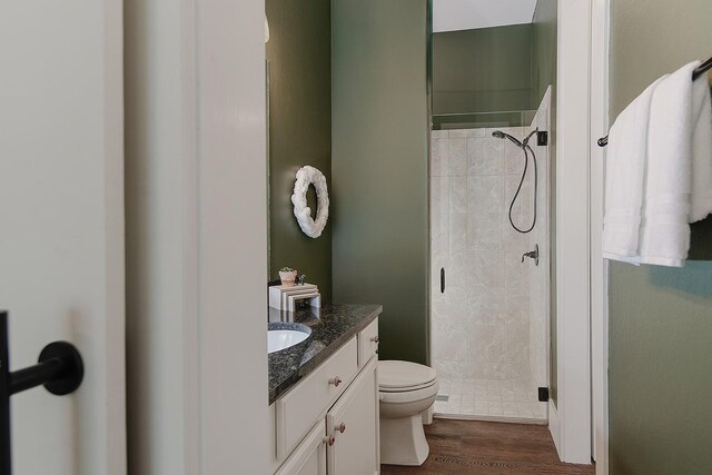 full bathroom featuring wood finished floors, toilet, a stall shower, and vanity