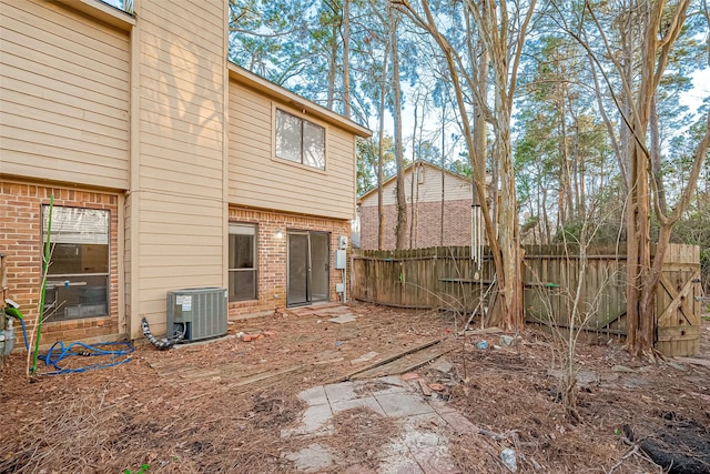 rear view of property with brick siding, central AC unit, and fence