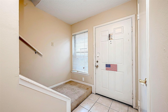 foyer with light tile patterned flooring, a healthy amount of sunlight, baseboards, and a textured ceiling