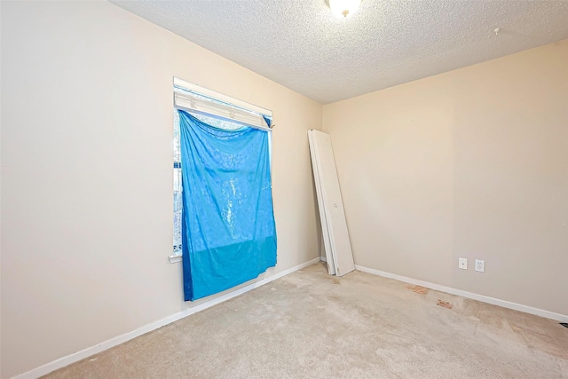 carpeted spare room featuring baseboards and a textured ceiling