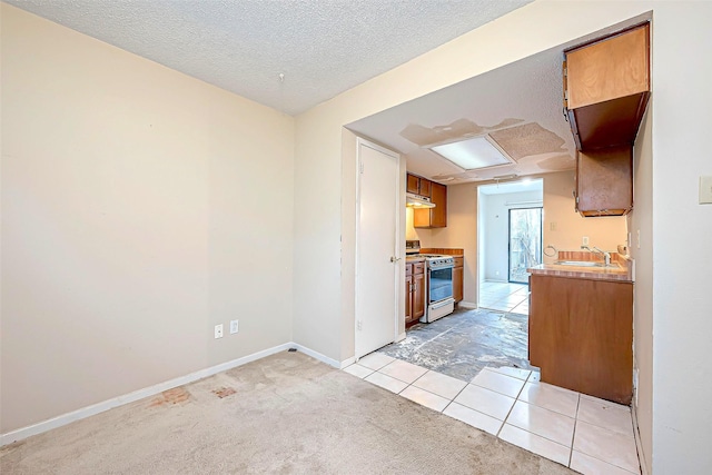 kitchen with a sink, a textured ceiling, light countertops, light colored carpet, and white range with gas stovetop