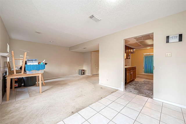 spare room with baseboards, light colored carpet, visible vents, and a textured ceiling