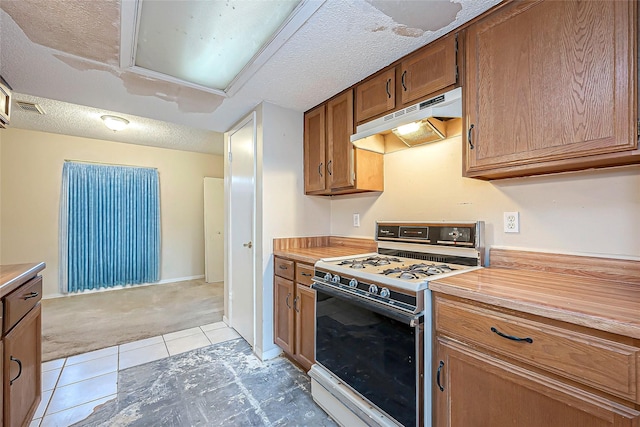 kitchen with visible vents, white gas range oven, under cabinet range hood, a textured ceiling, and brown cabinets