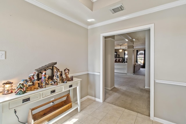 corridor with visible vents, crown molding, baseboards, light tile patterned floors, and light carpet