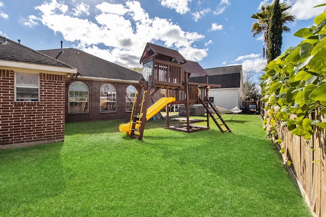 view of playground with a lawn and fence