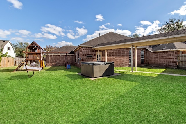 view of yard featuring a hot tub, a playground, and a fenced backyard