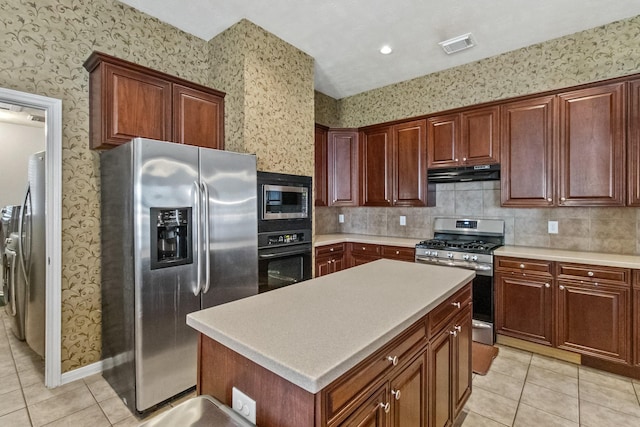 kitchen with under cabinet range hood, stainless steel appliances, visible vents, and wallpapered walls