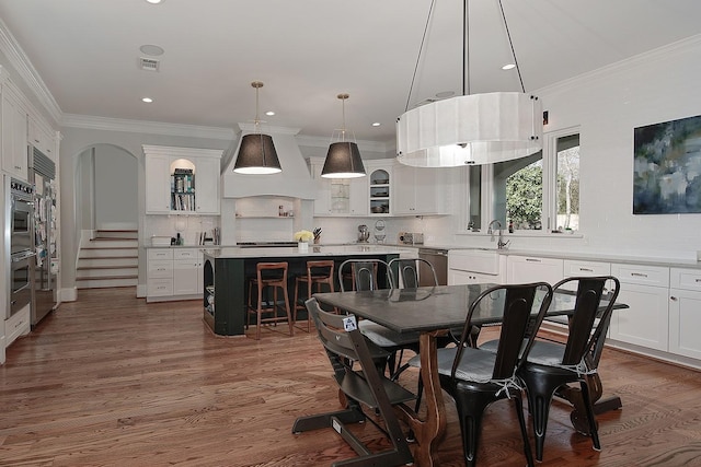 dining area with visible vents, arched walkways, wood finished floors, and crown molding