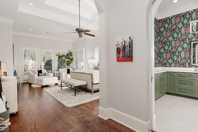 interior space featuring recessed lighting, arched walkways, light wood-style floors, crown molding, and a raised ceiling