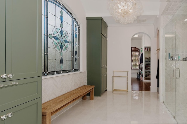 corridor featuring an inviting chandelier, visible vents, arched walkways, and ornamental molding