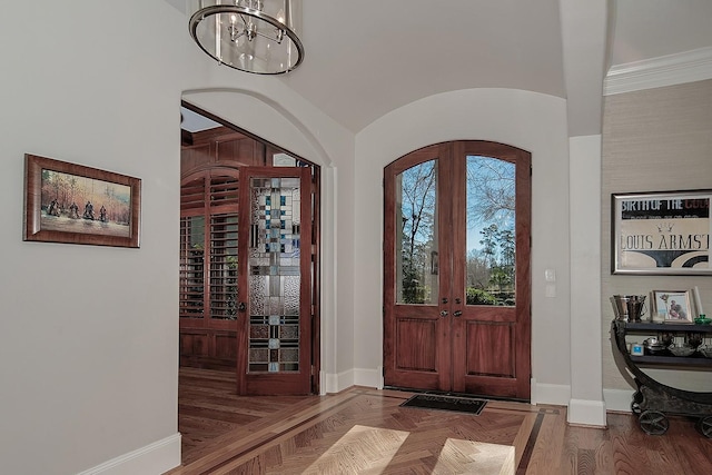 foyer with baseboards, lofted ceiling, parquet floors, french doors, and a notable chandelier