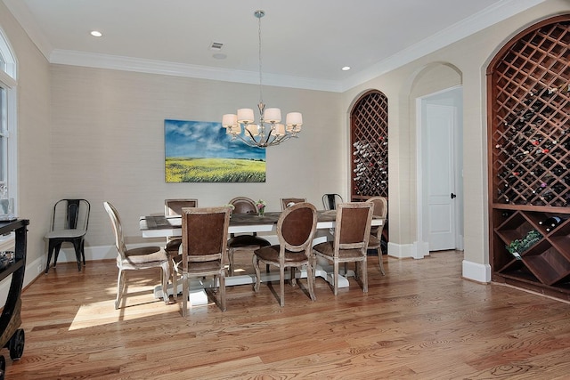 dining room with an inviting chandelier, baseboards, light wood-type flooring, and ornamental molding