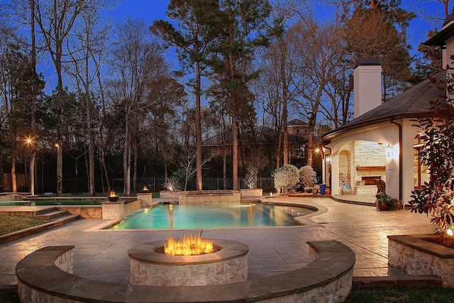 outdoor pool featuring a patio area, an outdoor fire pit, an outdoor stone fireplace, and fence