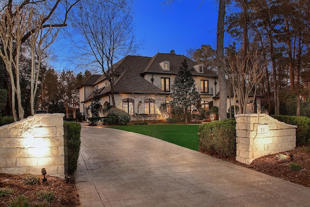 french country style house featuring concrete driveway, a front yard, and stucco siding