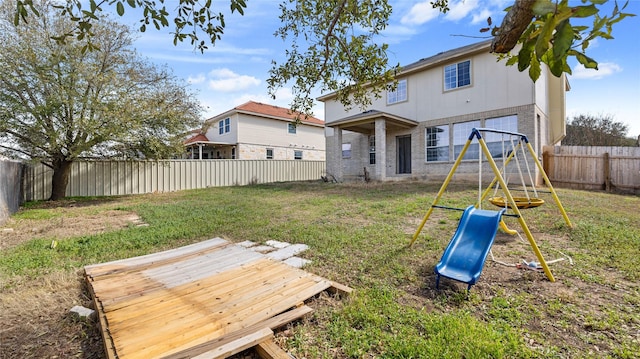 back of house featuring a playground, a fenced backyard, brick siding, and a lawn