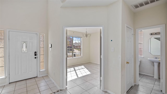 entrance foyer with light tile patterned floors, visible vents, baseboards, and an inviting chandelier