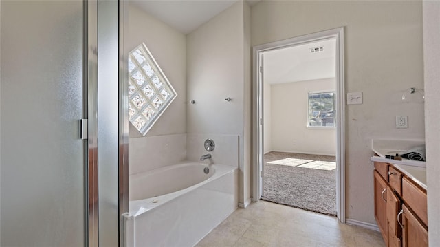 bathroom featuring visible vents, baseboards, a bath, and vanity