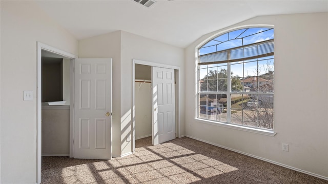 unfurnished bedroom featuring carpet floors, multiple windows, and vaulted ceiling