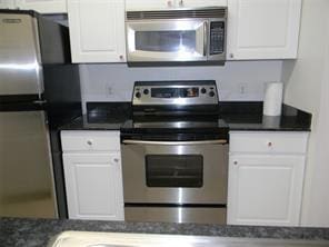 kitchen featuring dark countertops, white cabinets, and stainless steel appliances