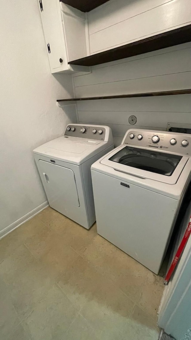 laundry room featuring washing machine and dryer, cabinet space, and baseboards