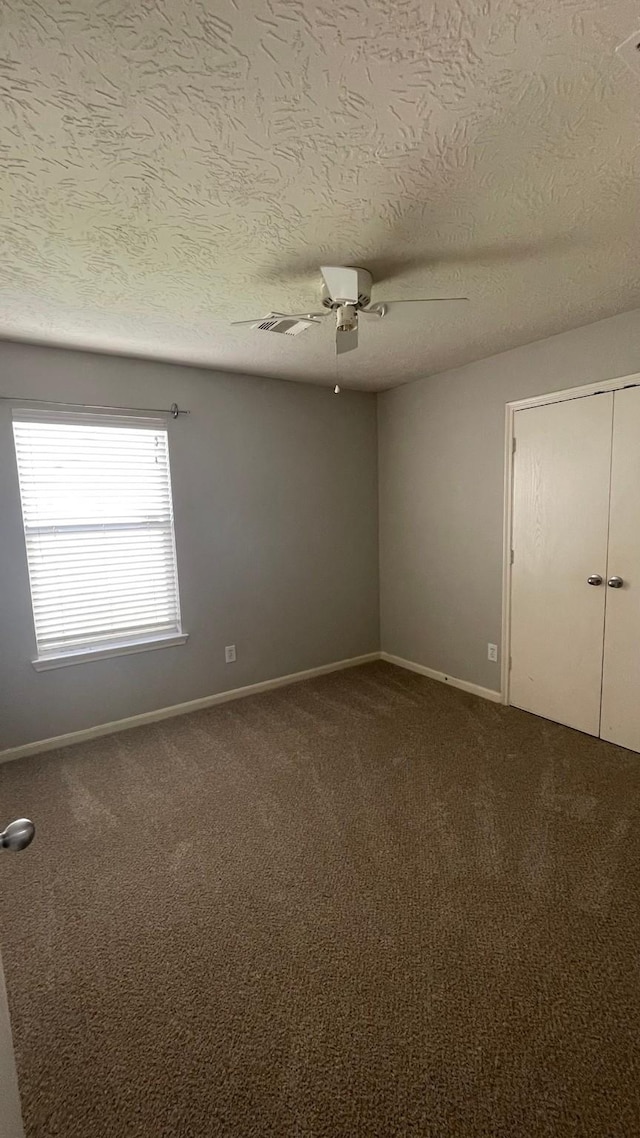 unfurnished room featuring baseboards, ceiling fan, and dark carpet