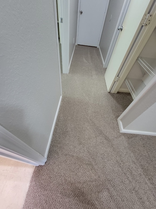 hallway featuring baseboards and carpet