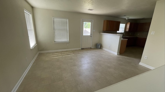 interior space featuring brown cabinetry, plenty of natural light, light floors, and baseboards