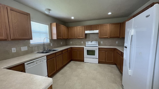 kitchen featuring a sink, white appliances, under cabinet range hood, and brown cabinetry