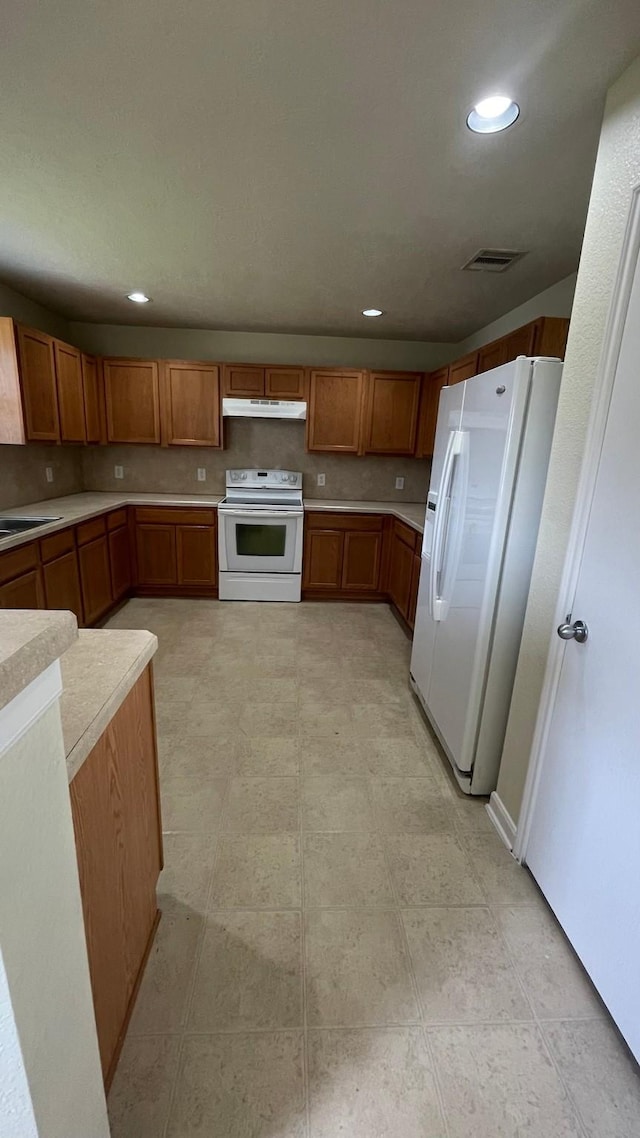 kitchen featuring under cabinet range hood, visible vents, white appliances, and light countertops